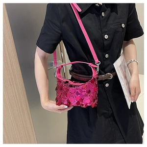 Detail of pink sequin shoulder bag with large reflective scales on black dress