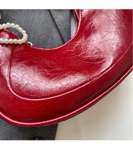 Close-up of red pleated dumpling bag with elegant white pearl decorative handle