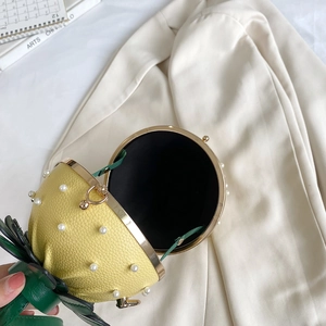 Unique yellow strawberry-shaped handbag featuring white pearls and green leaf accents