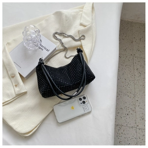 Detail of black rhinestone crescent bag featuring silver chain strap and knot handle