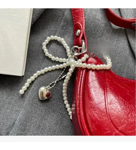Detail of red patent leather crescent bag with pearl bow and silver heart pendant