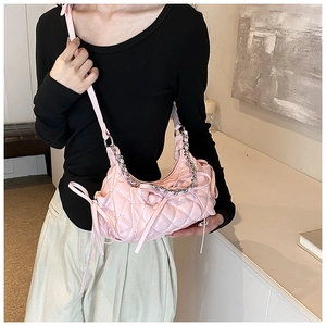 Detail of pink quilted hobo bag featuring decorative ribbons and a stylish chain handle