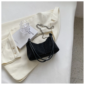 Detail of black rhinestone crescent bag with silver chain on beige blazer setting