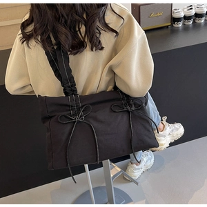 Detail van zwarte shopper met witte contrasterende strikken en geplooide schouderriem
