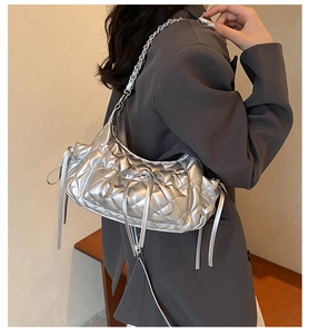 Detail of silver metallic quilted shoulder bag with ribbon bows and chain strap