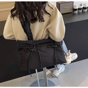 Detail van zwarte canvas shopper met witte strikjes en geplooide ruches schouderband
