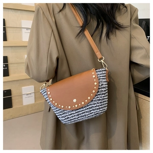 Detail of woven saddle bag with houndstooth fabric and brown leather riveted flap