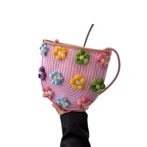 Pink hand-knit crochet shoulder bag with colorful floral patterns and thin rope strap