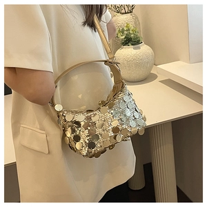 Detailed view of shimmering gold sequin crescent handbag worn over the shoulder