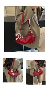 Detail of red crescent underarm bag with glossy finish and elegant pearl pendant