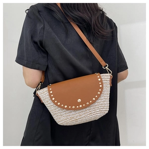Detail of woven crescent crossbody bag with brown leather lid and gold stud accents