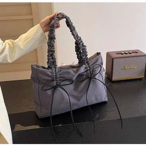 Detail van grijze nylon shopper met geplooide handgrepen en elegante zwarte strikken