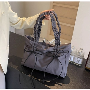 Detail van donkergrijze shopper met geplooide handgreep en zwarte strikaccenten