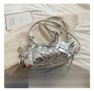 Detail of silver quilted crossbody bag with metal chain and bow decoration
