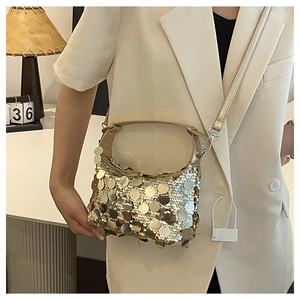 Detail of a gold sequin crossbody bag showing its metallic texture and detachable strap