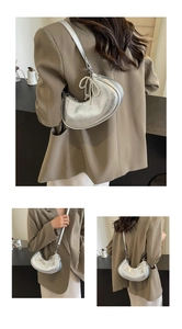 Detail of silver crescent bag with metallic finish and decorative pearl bow charm