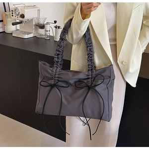 Detail van de grijze nylon draagtas met geplooide handvatten en elegante zwarte strikken