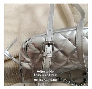 Detail of silver quilted shoulder bag featuring adjustable leather strap and tassel accents