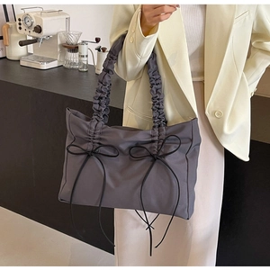 Detailweergave van grijze nylon draagtas met geplooide handvatten en zwarte strikken