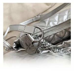 Macro shot of silver quilted bag with round metal hook and chain strap detail