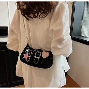 Detail of Y2K aesthetic black shoulder bag with pink star patch and metal charms