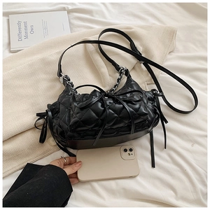 Close-up of black quilted rhombus crossbody bag with bow detail and chain strap