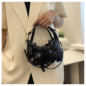 Close-up of black sequined crescent handbag with silver metal buckles and leather strap