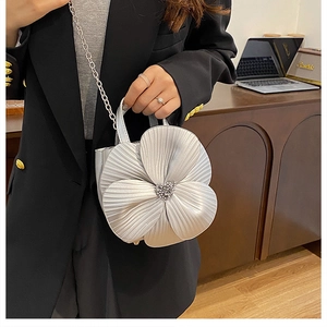 Detail of silver floral bucket bag with 3D petals and pearl stamen held by a model