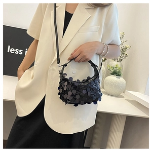 Detailed shot of a black sequined shoulder bag with large metallic paillettes on model