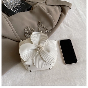 Macro shot of 3D floral petals and metal rivets on a white designer bucket bag