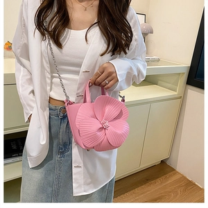 Detail of pink mini bucket bag with 3D flower and silver chain strap on a model