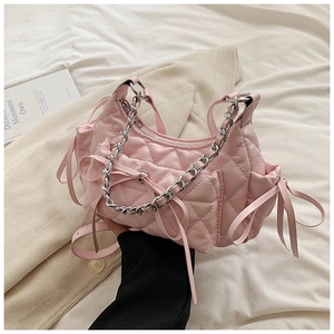 Detail of pink quilted shoulder bag with silver chain handle and leather bow decoration