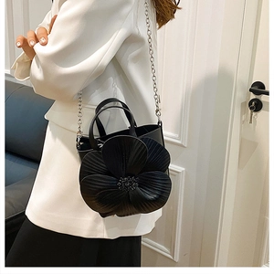 Detail of elegant black PU leather handbag featuring a large 3D floral fold design and chain