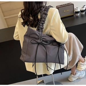 Detail van donkergrijze nylon tas met plooien, strikjes en stijlvolle schouderband