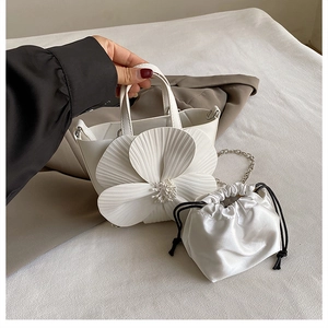 Detail of white bucket bag with large floral design and silver chain strap