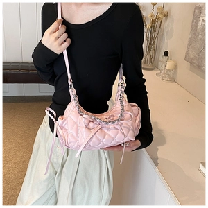 Detail of pink quilted shoulder bag with silver chain and decorative ribbon bow