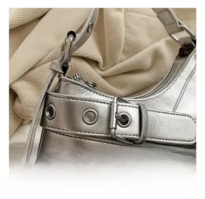 Gros plan du sac à bandoulière argenté Y2K avec boucle métallique et détails d'œillets
