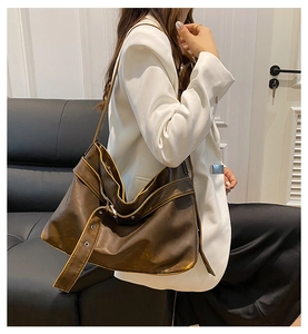 Detail of dark brown leather hobo bag with yellow stitching and decorative buckle strap