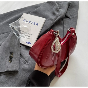 Detail of burgundy hobo bag with pearl pendant, shiny leather texture and silver zipper