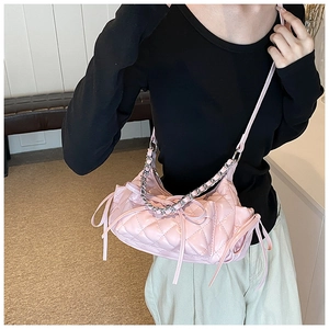 Pink quilted crossbody bag with ribbon bows and silver chain strap shown on model