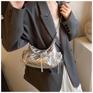 Close-up of silver quilted crossbody bag featuring delicate ribbon bow and chain strap