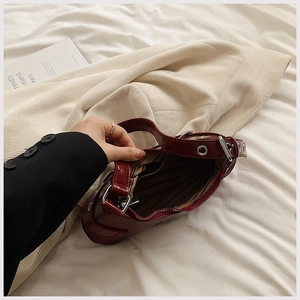 Détail du sac bordeaux montrant la doublure rayée et la poche intérieure zippée