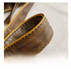Macro detail of high-quality brown leather bag strap with precise yellow stitching