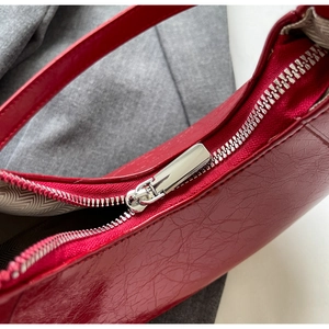 Macro detail of red glossy bag showing silver zipper and herringbone fabric lining
