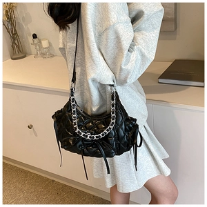 Detail of black quilted shoulder bag with silver chain and bow ribbon accents