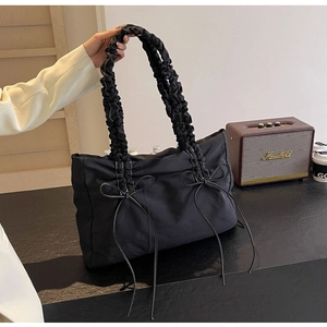 Detail van zwarte nylon draagtas met geplooide handvatten en witte strikdetails