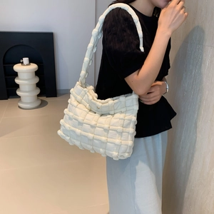 Detail of cream woven puff shoulder bag showing the textured puffy grid pattern on a model