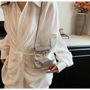 Silver metallic crossbody bag with chain strap shown on a model in casual attire
