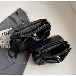 Detailed interior of black leather tote bag with silver lock and multi-compartment design