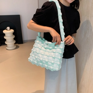 Detail of mint green puffed shoulder bag with quilted square texture and wide strap